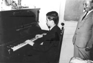 Ο Δημήτρης Χούπας σε εφηβική ηλικία εξασκείται στο πιάνο υπό την επίβλεψη του πατέρα του Νικόλαου Χούπα. Κάντε click για μεγέθυνση.